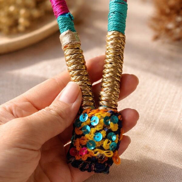 Collier artisanal fait main avec sequins colorés et fils tissés. Bijou textile unique, bohème chic.